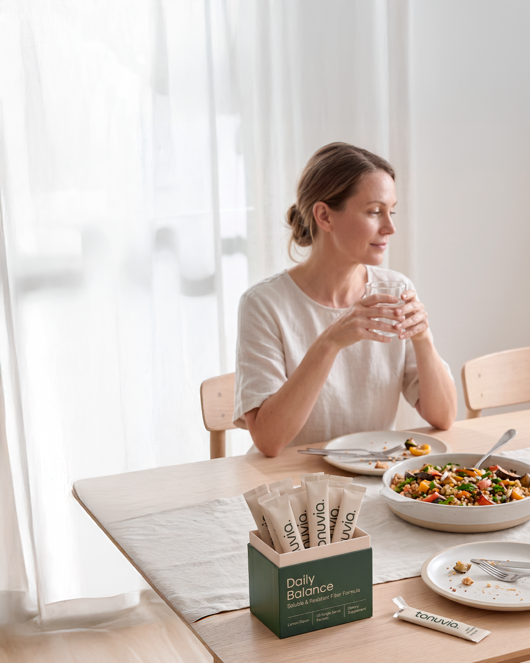 Tonuvia Daily Balance single-serve sticks beside a meal and a glass of water.